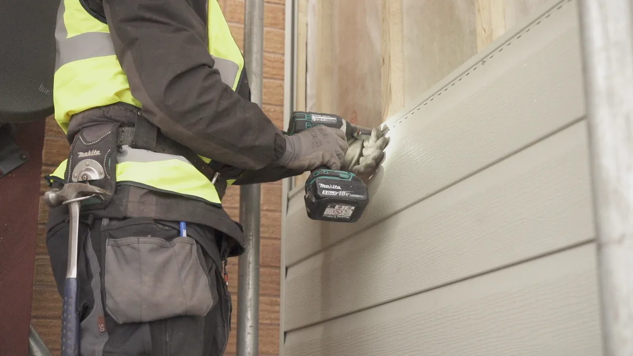 Cladding being installed on an exterior wall